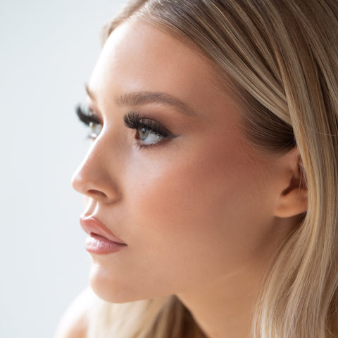 Lithe Lashes Bold Collection Style B3 - Kabuki, an image of a model’s face wearing lithe lashes on both eyes, with full makeup, looking from a left side profile, semi zoomed in, displaying the elegance of the lashes on her eyes.