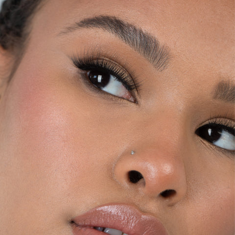 Lithe Lashes Bold Collection Style B5 - Fine & Fluttery, an image of a model’s face wearing lithe lashes on both eyes, with full makeup, looking from a right side profile, semi zoomed in, displaying the elegance of the lashes on her eyes.