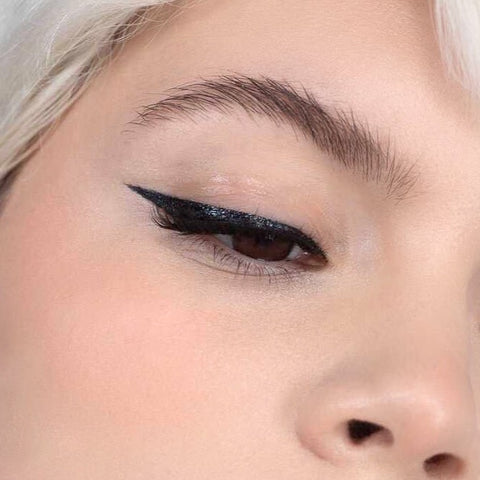 Lithe Lashes false lashes accessories Grip Liner, a 2-in-1 eyeliner lash adhesive. The model is wearing Lithe lashes and has used Grip Liner to apply the lashes to her eyes, also showing the eyeliner along the contour or her eyes as well.