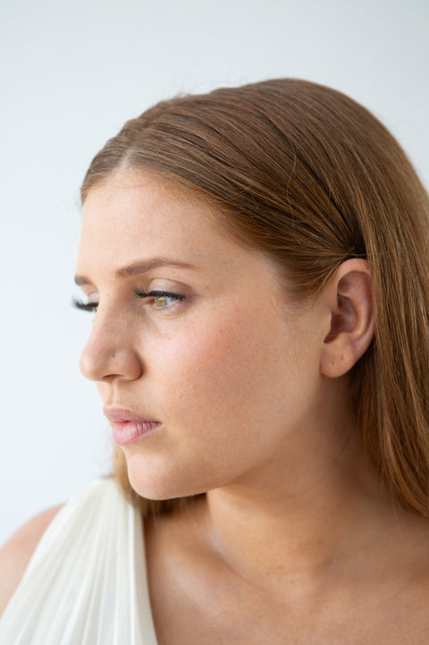 Blog_Lithe Lashes_ Lash Extensions vs. Strip Lashes_Featured Image_Face shot of model, close up, wearing Lithe Lashes, grey backdrop, white sash