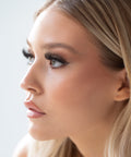 Lithe Lashes Bold Collection Style B3 - Kabuki, an image of a model’s face wearing lithe lashes on both eyes, with full makeup, looking from a left side profile, semi zoomed in, displaying the elegance of the lashes on her eyes.