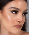 Lithe Lashes Bold Collection Style B4 - Wispy & Bold, an image of a model’s face wearing lithe lashes on both eyes, with full makeup, looking from a right side profile, semi zoomed in, displaying the elegance of the lashes on her eyes.